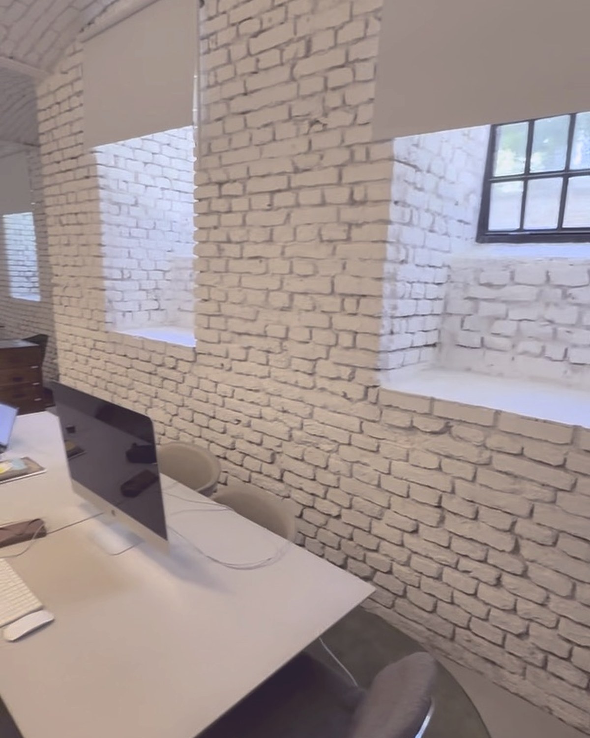 A bright desk setup below the arched brick windows