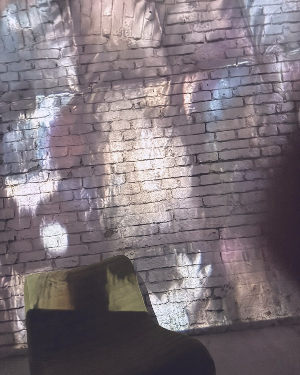 Coloured light projected across the white brick wall