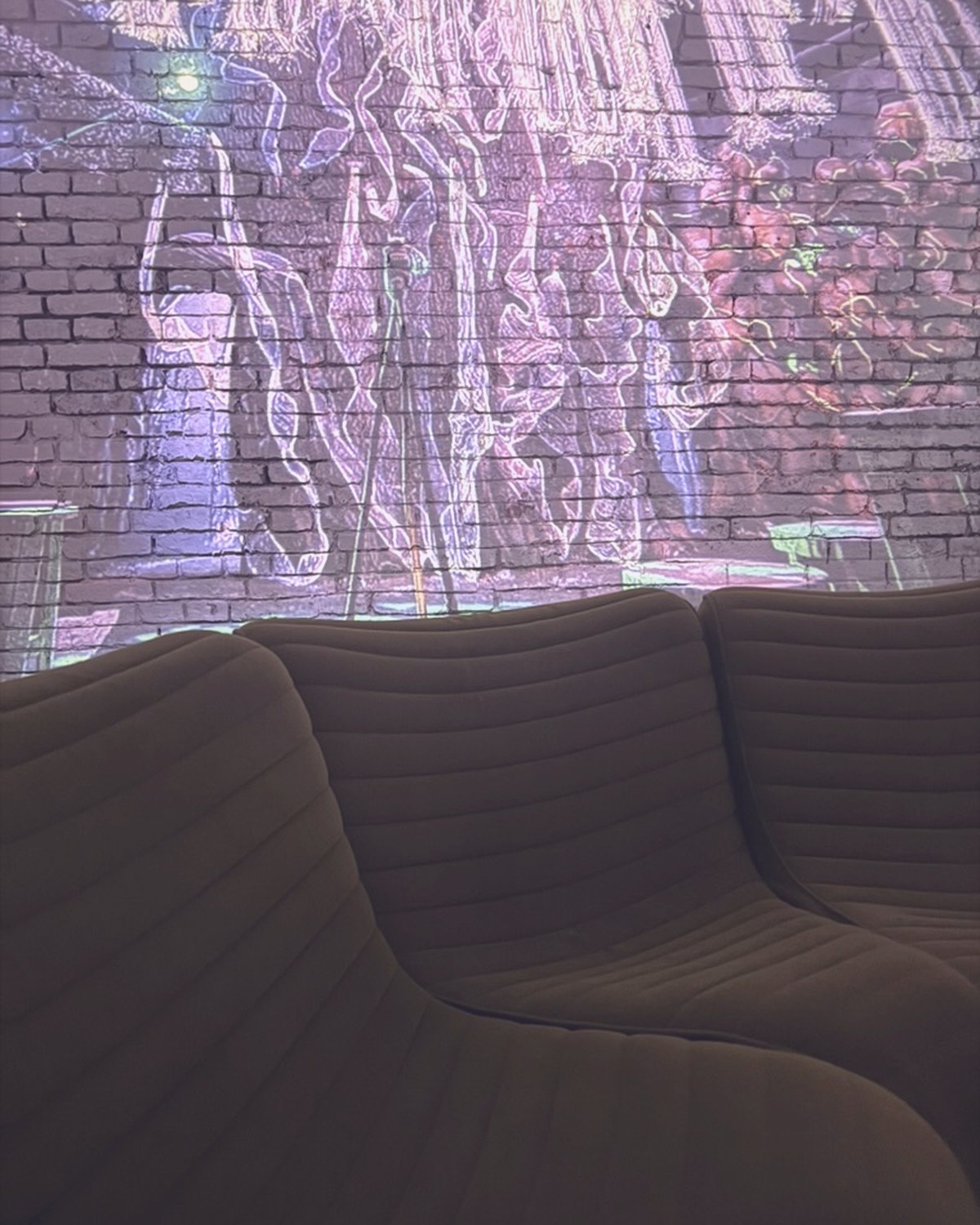 Colourful figures projected onto brick behind the lounge