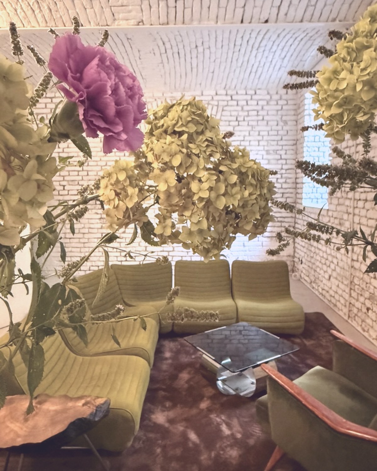 The green lounge framed by hydrangeas and brick arches